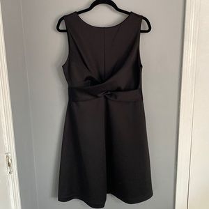 Black scuba style short a-line dress with a gold zipper and twisted waist detail